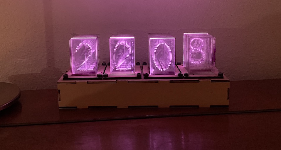 Image of the clock, 4 sets of 10 transparent acrylic panes with numbers 0-9 etched on them. Individual panes are illuminated from below to display the current times
